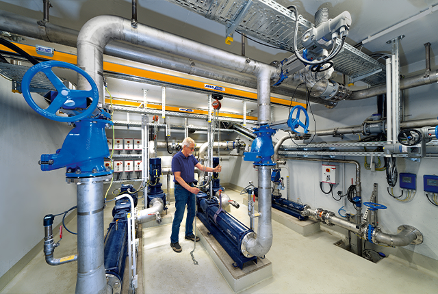 Pracownik obsługuje system przenośników podwieszonych z wciągnikiem łańcuchowym i przemieszcza ładunek w hali produkcyjnej