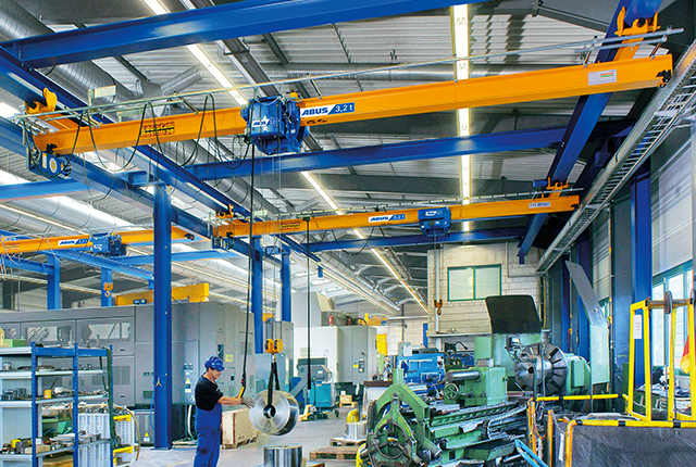 Suwnica podwieszana ABUS w hali przemysłowej o udźwigu do 8 t i rozpiętości do 25 m, zapewniająca oszczędność miejsca podczas transportu materiałów.