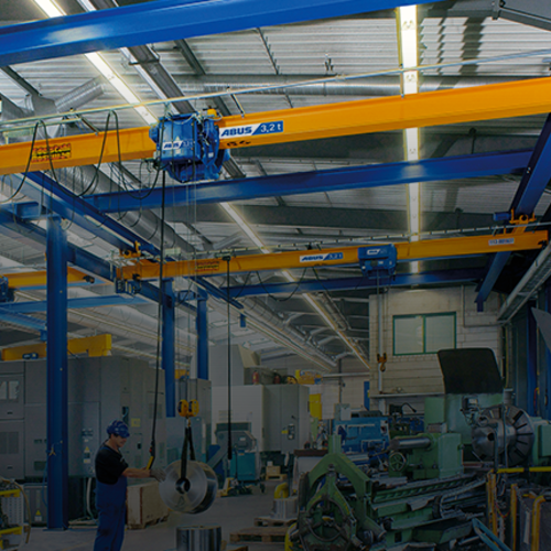 Suwnica podwieszana ABUS w hali przemysłowej o udźwigu do 8 t i rozpiętości do 25 m, zapewniająca oszczędność miejsca podczas transportu materiałów.