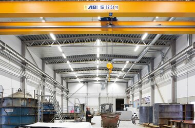Nowoczesna hala przemysłowa wyposażona w suwnicę pomostową ABUS (12,5 t) oraz haki do transportu, zapewniające wydajny transport materiałów w obszarze produkcyjnym.